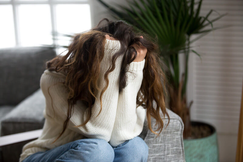 Anxious woman sitting with her head in her hands