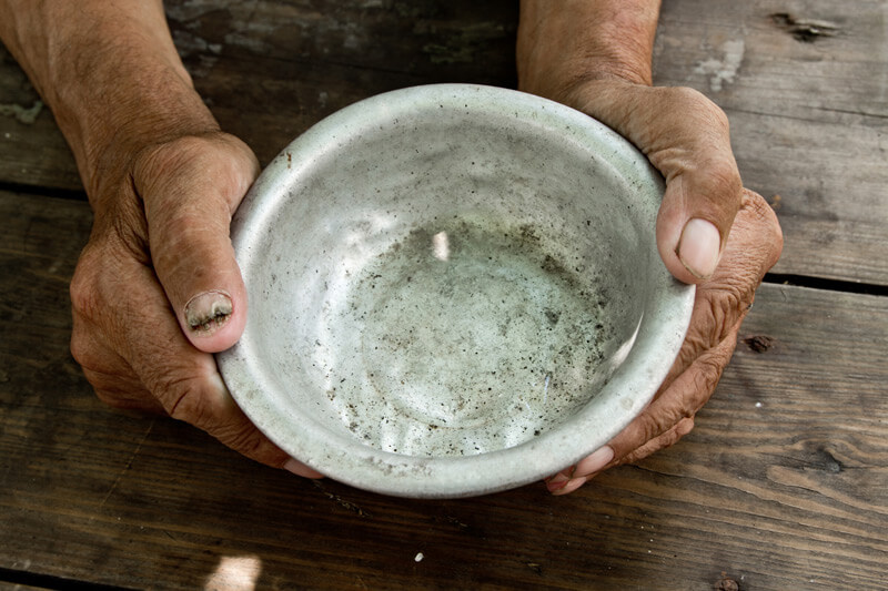 Elderly hands holding an empty bowl