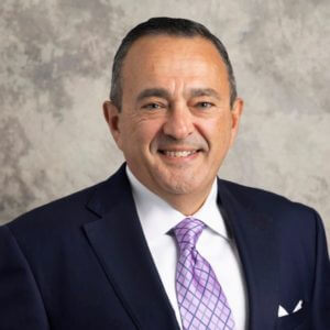 Smiling man in a suit and purple tie, larger portrait